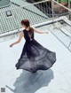 A woman in a black dress is standing on a rooftop.