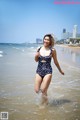 A woman in a bathing suit running into the ocean.